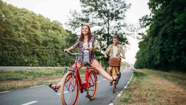 Young man and woman walking on retro bikes